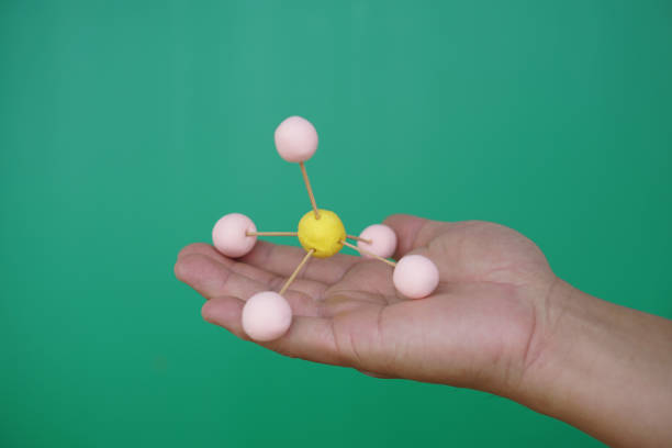 Closeup hand hold DIY molecule structure made from toothpicks and plasticine. Concept, teaching aids, educational materials. science lesson about molecule. Creative task from learning.