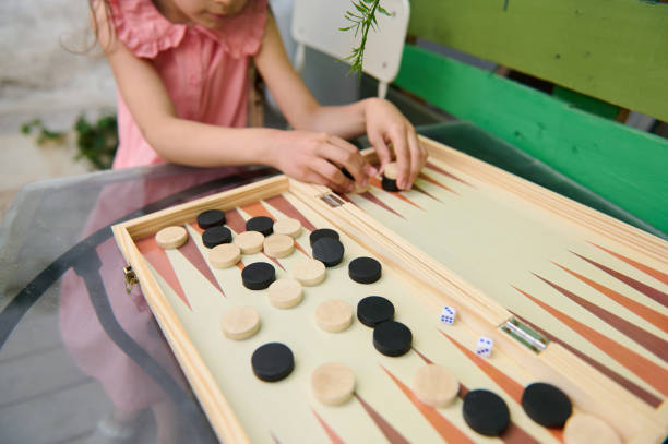 istock Child playing backgammon on a wooden board in a casual outdoor setting 2164653172