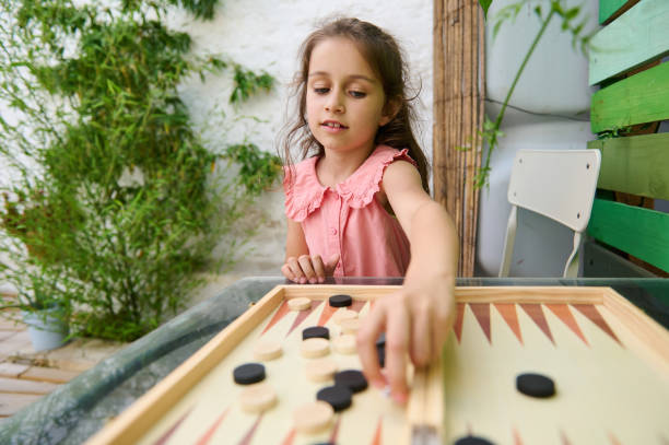 istock Young girl playing backgammon in a garden setting on a sunny day 2164653175
