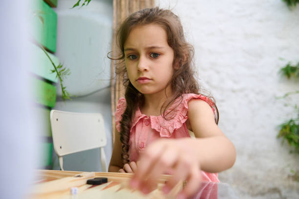 istock Young girl playing a board game outdoors with a focused expression 2164653316