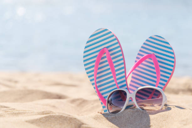 istock Flip flops and shades on the sea beach 2164654116