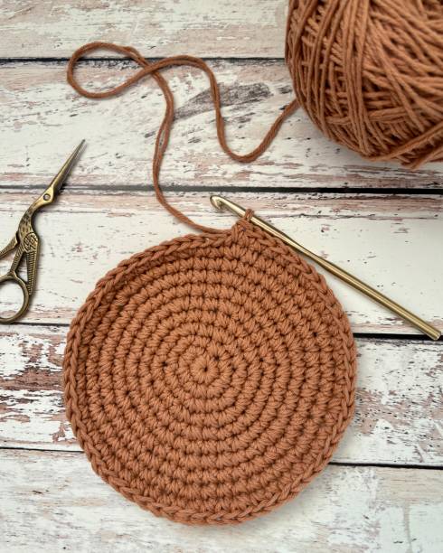 istock Unfinished crochet round shape placemat on a wooden surface 2164655138