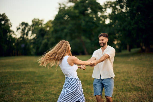 istock Happy couple having fun, spinning around at the park. 2164658028