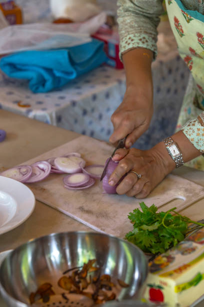 istock Indian woman hands cuts onion on cutting board at kitchen table 2164658739