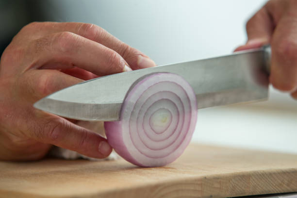 istock man's hands slicing an onion on wooden cutting board 2164658741