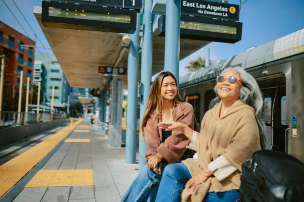 Mom and daughter going for a train ride - staycation in California, using sustainable ways of traveling. They are using the Pacific train lines and Los Angeles commuter trains for a quick nature getaway together.