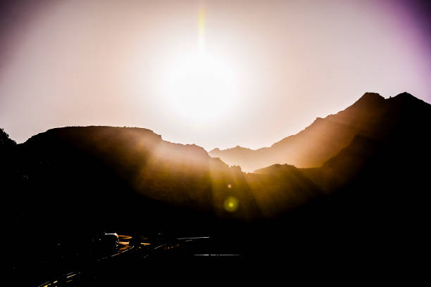 Sun atop a mountain in the eastern sky casting orange color everywhere