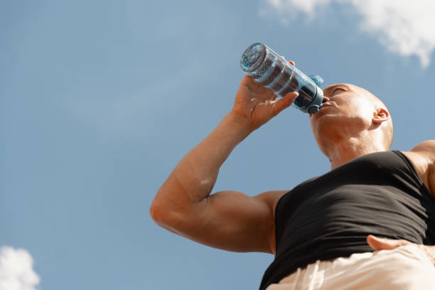 istock Athletes man drinking water on against sky. Outdoors. Water balance for for active workout. 2164661888