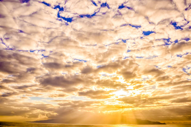 The sky is filled with clouds and the sun is shining brightly. The clouds are scattered throughout the sky, with some closer to the horizon and others higher up