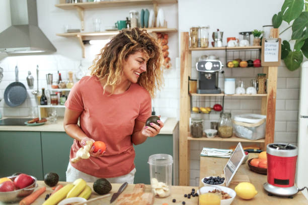 istock Young smiling beautiful woman using digital tablet while preparing healthy meal in a domestic kitchen 2164673405