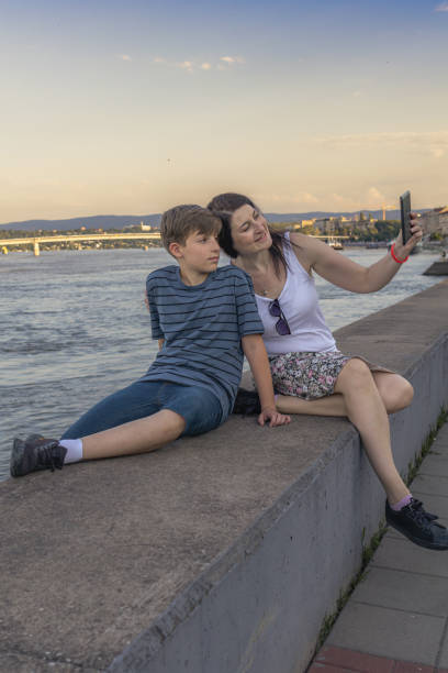 istock Mother and son are enjoying by the river at sunset and using digital tablet for video call. They are having fun and enjoying in precious moments together. 2164675416
