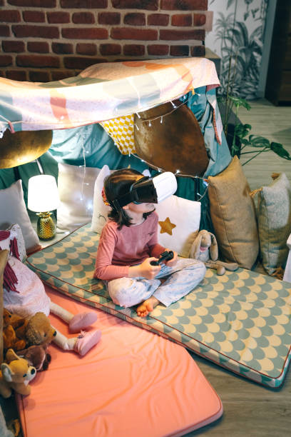 istock Digital native with virtual reality glasses watching 3D video sitting over mat in a tent at home 2164686564
