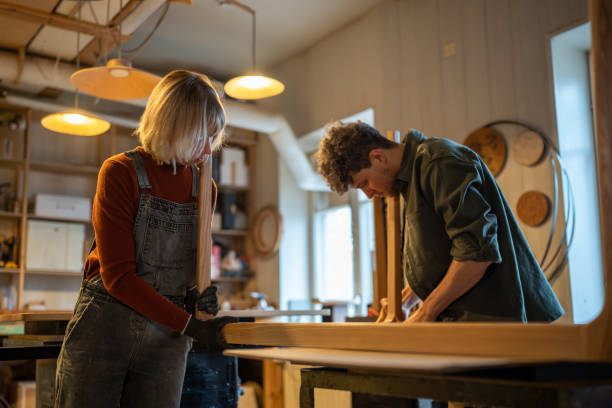 istock Carpentry workshop, craftsmen working together. Woman and man assembling table, connecting parts 2164698074