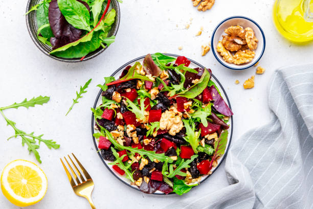 istock Fresh crispy vegan salad with baked beetroot, dried prunes, arugula, chard and lnuts, white background 2164700659