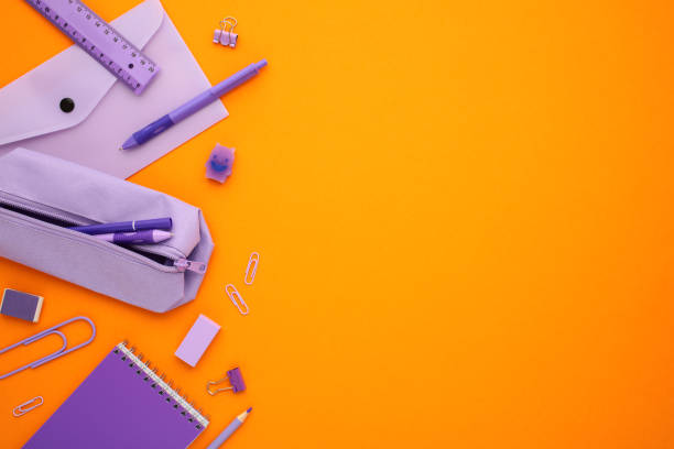 istock Purple pencil case with pen, pencil, notebook, clips, envelope on orange background. Back to school concept. Flat lay, top view, copy space. 2164701142