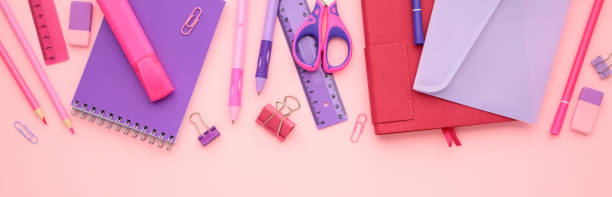 istock Row of different school items on pink background. Flat lay paper notebook, ruler, scissors, pen, pencil, envelope. 2164701376
