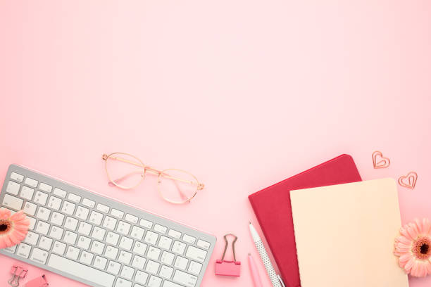 istock Chic office desk with trendy accessories. Flat lay keyboard, paper notebooks, eyeglasses and flowers on pink backdrop. Perfect for lifestyle bloggers 2164701801