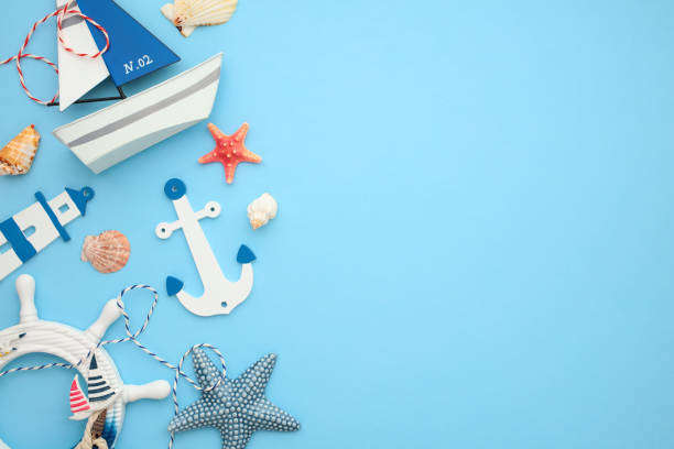 istock Flat lay composition with anchor, sailboat, sea wheel, lighthouse and seashells on blue backdrop. Ideal for travel and nautical themes 2164702903
