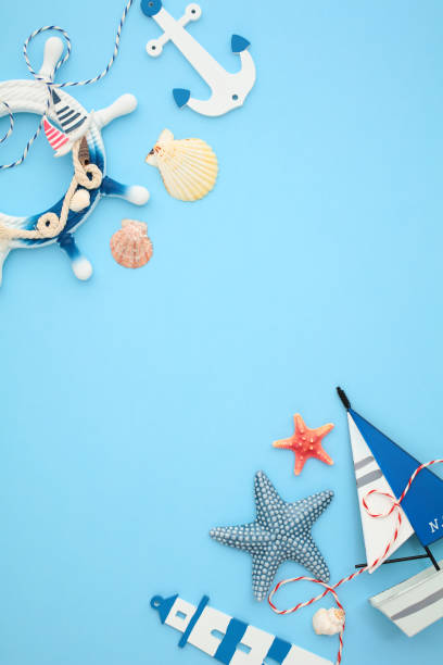 istock Flat lay nautical themed composition with lighthouse, anchor, starfishes, seashells and a sailboat on blue background. Ideal for marine-themed projects 2164703162