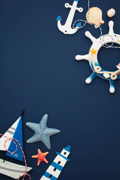 istock Nautical flat lay composition with anchor, shells, lighthouse, starfish and sailboat model on navy blue backdrop. Ideal for maritime design 2164703357