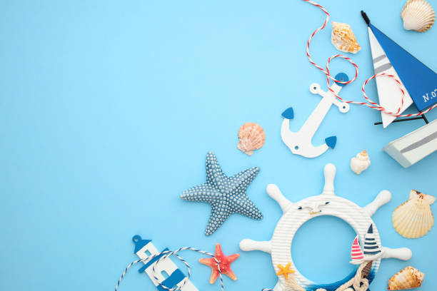 istock Nautical flat lay composition with wheel, lighthouse, sailboat, starfish, seashells on light blue background. 2164703404