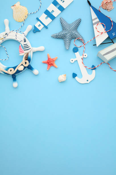 istock Nautical themed decor on a blue backdrop featuring anchors, sea wheel, seashells, a boat, and a lighthouse. Perfect for summer, beach, and travel themes 2164703524