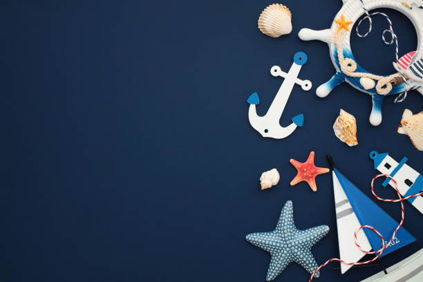 istock Nautical themed photo featuring anchor, shells, lighthouse, starfish and sailboat model on navy blue backdrop. Ideal for maritime design 2164703545