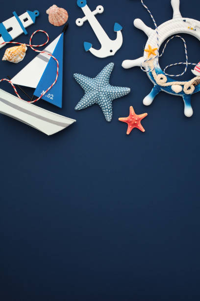 istock Nautical vertical composition with a ship’s wheel, lighthouse, anchor, starfish, seashells, and a sailboat model. Flat lay, top view. 2164703553