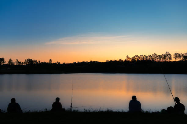Two Vietnamese men sit to fish at sunset in the lake in Reunification Park in central Hanoi, Vietnam.