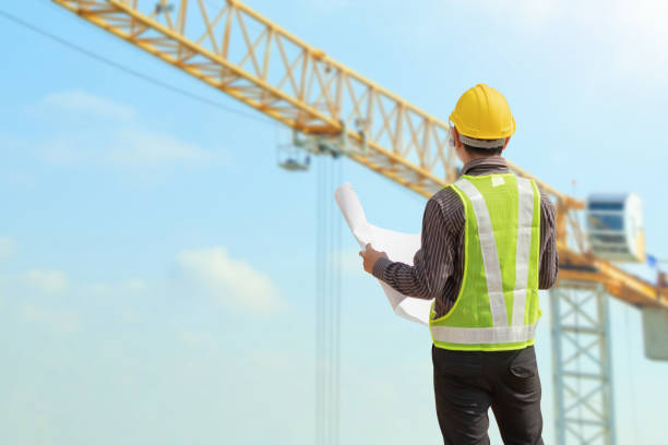 istock construction engineer worker in protective helmet and blueprints paper on hand at building site background 2164712140