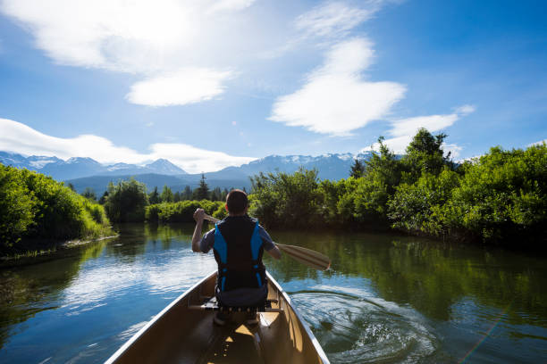 istock Man dog canoe on tranquil lake at sunrise 2164713056