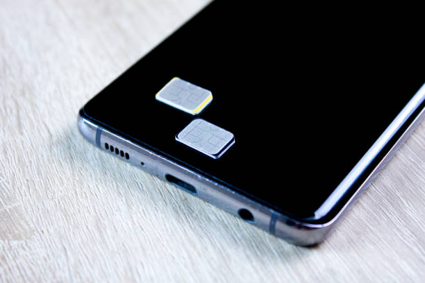 istock 2 sim card next to the smartphone on the table. SIM card cellular communication, operator 2164713762