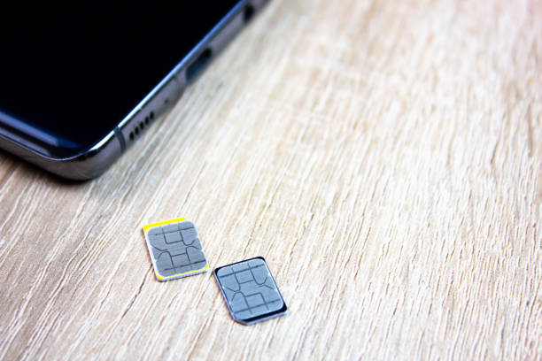 istock 2 sim card next to the smartphone on the table. SIM card cellular communication, operator 2164713763