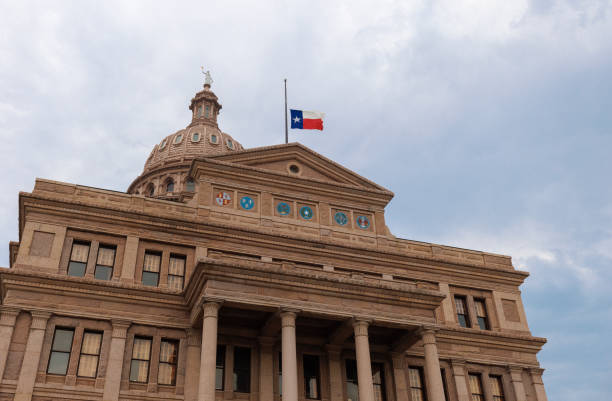 closer look of the Texas state capitol building's dome with waving flags of the United States and Texas