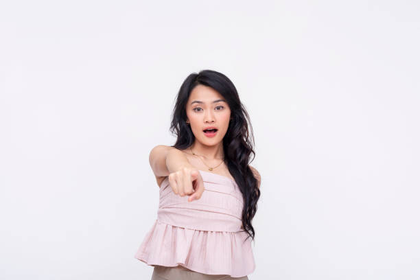 istock A surprised young asian woman looking at the camera pointing forward. Isolated on a white background. 2164721629