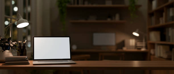 istock A front view image of a laptop computer mockup on a wooden table in a dark office. 2164723969