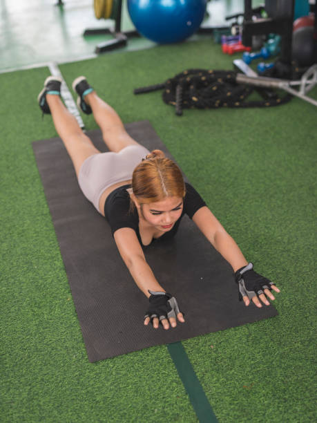 istock A young asian lady does superman back extensions on a black mat. Isometric exercise. Working out and training lower back muscles at a home gym. 2164731287
