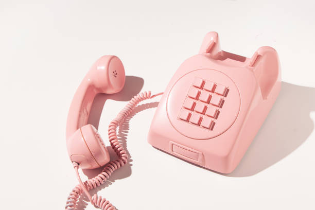 Vintage pink telephone and female hand on pink background, top view