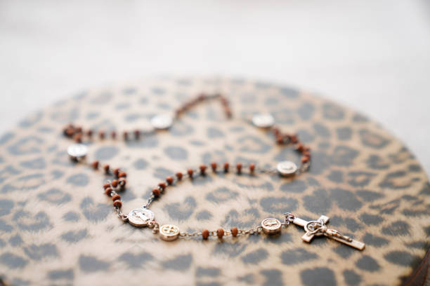 A necklace with a cross and a star on it is on a leopard print surface. The necklace is made of beads and has a silver chain