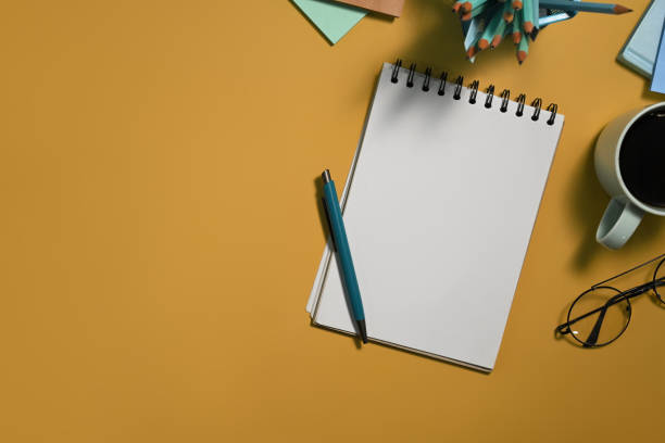 istock Blank notepad, pen, glasses and cup of coffee on yellow background with copy space 2164750131