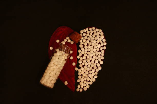Homoeopathy concept by bottle and pills. A creative photography for homoeopathy concept. Half heart shape is filled with pills and glass bottle with pills placed on other half of heart. Homoeopathy healthcare system. rajkot india stock pictures, royalty-free photos & images