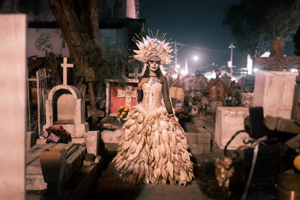 A skeleton bride is posing in a cemetery during Day of the Dead celebration