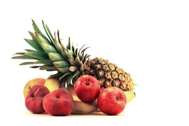 A vibrant collection of fruits includes a pineapple, bananas, apples, and an orange, arranged aesthetically against a light backdrop.
