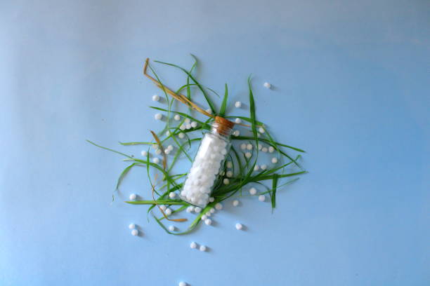 The natural way the homoeopathy way. Healthcare and medicine. A glass bottle, homoeopathic pills and leaves on the blue background. Homoeopathic healthcare system. rajkot india stock pictures, royalty-free photos & images
