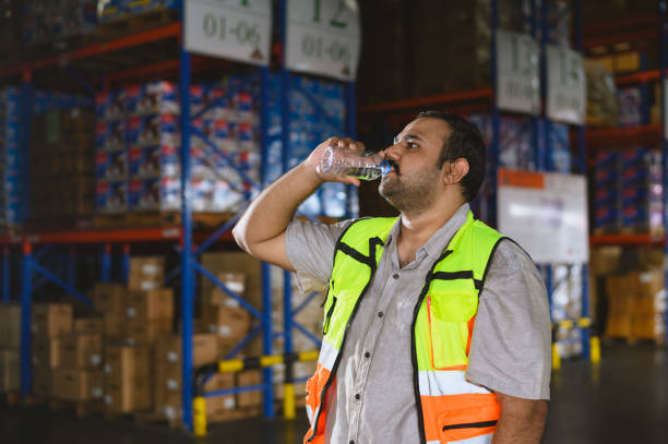 istock Time of rest from work. Tired warehouse employees man drinking water and resting after working at warehouse factory workplace. 2164760261