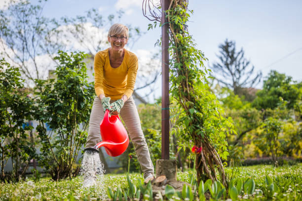 Happy senior woman enjoys watering plants in her garden.