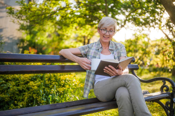 istock Senior woman reading book and drinking coffee 2164767372
