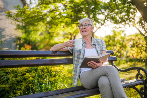 istock Senior woman reading book and drinking coffee 2164767375