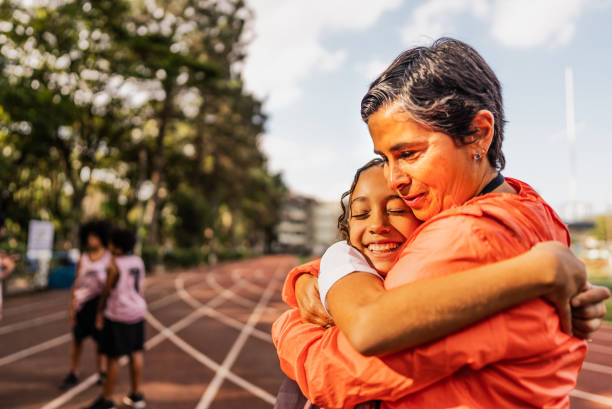 istock Instructor and girl athlete embracing on a running track 2164767565