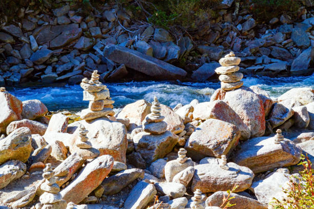 Rocky banks of stream with melted ice water. Thundering stream flows into the Krimml Falls valley. Mountains covered with evergreen forest.